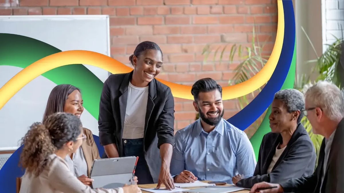 A diverse team of colleagues smiling around a meeting table in an office setting, framed by smooth, curving 3D ribbons in green, yellow, and blue.